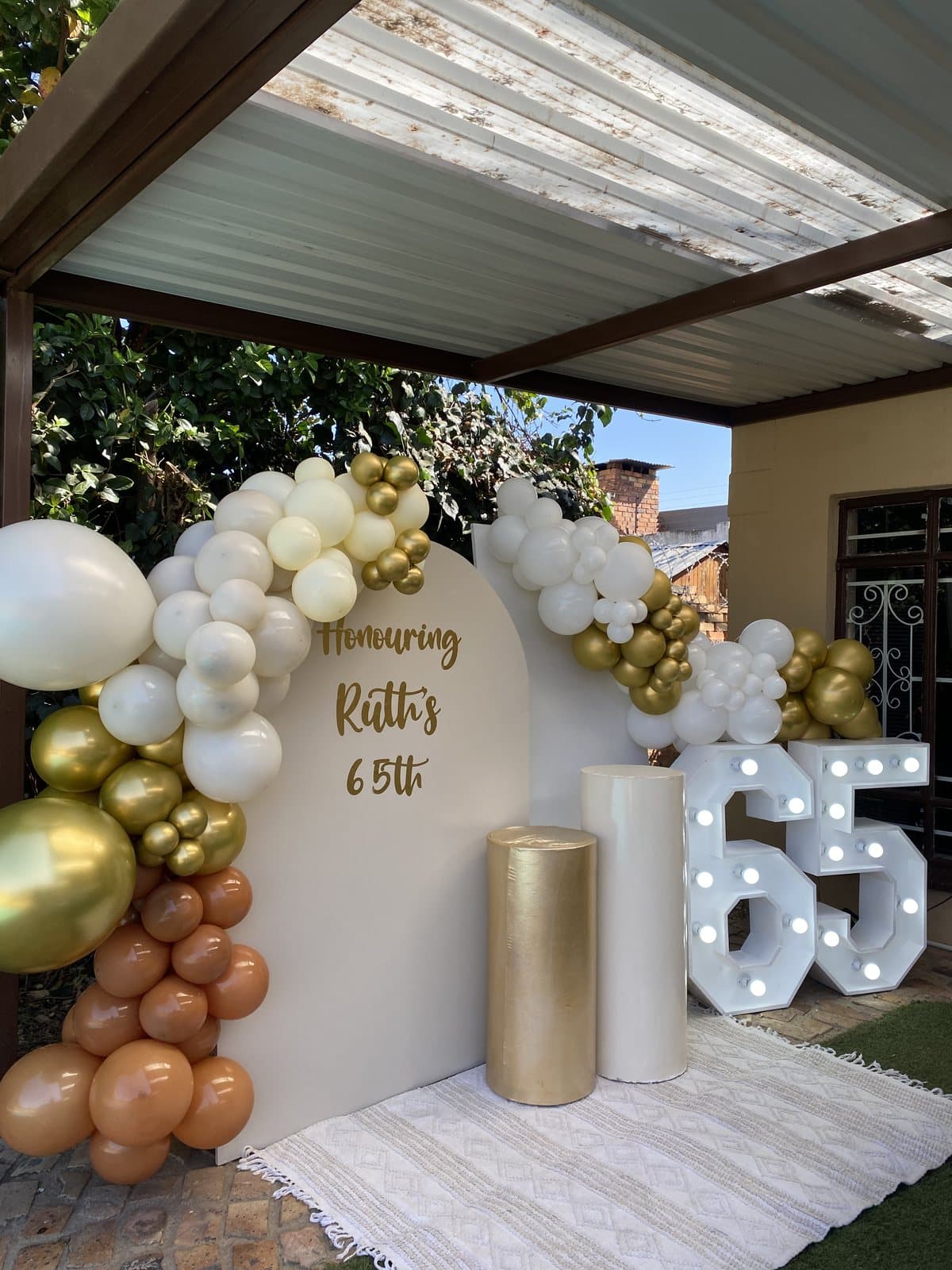 Gold and white balloon arch with a 65 marquee for a sixty-fifth birthday